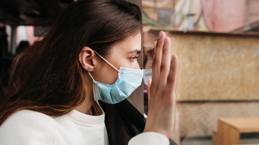 Una joven hipocondríaca mira desde la ventana durante la pandemia