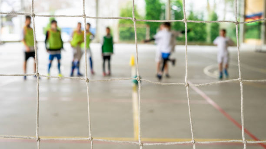 Group of children practicing futsal kicking the ball into the empty goal. Selective focus. High quality phot