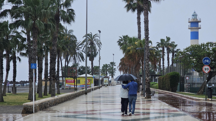 Varias personas pasean bajo la lluvia por el paseo marítimo de Torre del Mar, en Vélez-Málaga