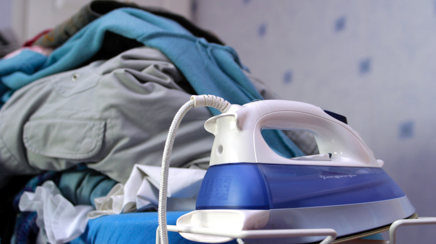 Montaña de ropa para planchar sobre la tabla de planchar con la plancha