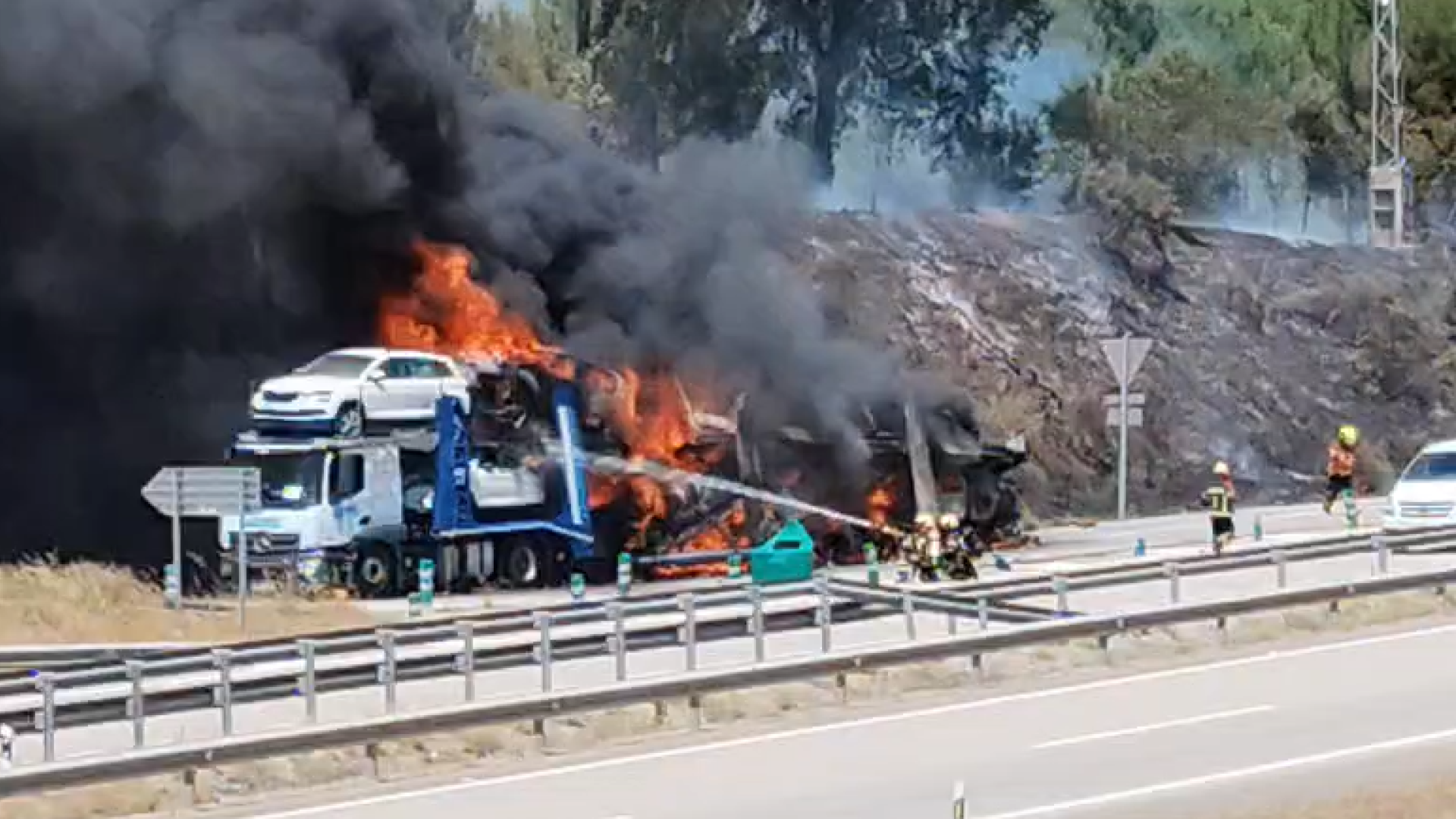 Un camión portacoches en llamas en la carretera de