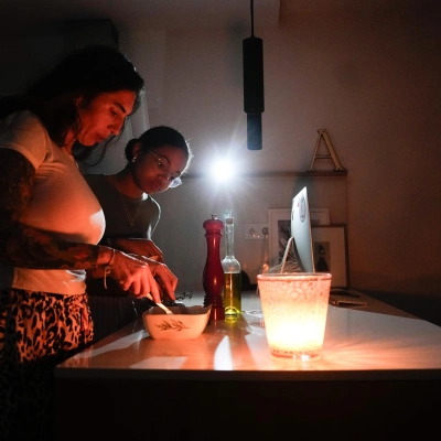 Una familia prepara la cena con ayuda de una vela la pasada noche en la localidad de El Masnou (Barcelona) durante el gran apagón que ha afectado a España