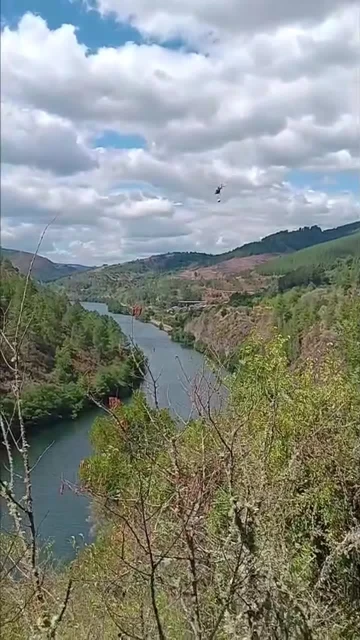 Un helicóptero de extinción capta agua en el río para sofocar el incendio que afecta a Quiroga (Lugo)