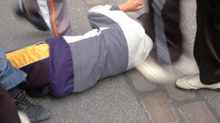 Jóvenes pegando patadas a un chico tirado en el suelo indefenso