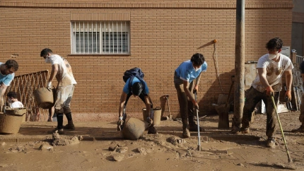 Varios jóvenes trabajan para despejar una calle de Paiporta