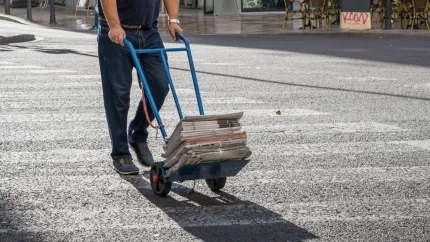 Un repartidor empuja un carrito de mano por una calle en Valencia, España.