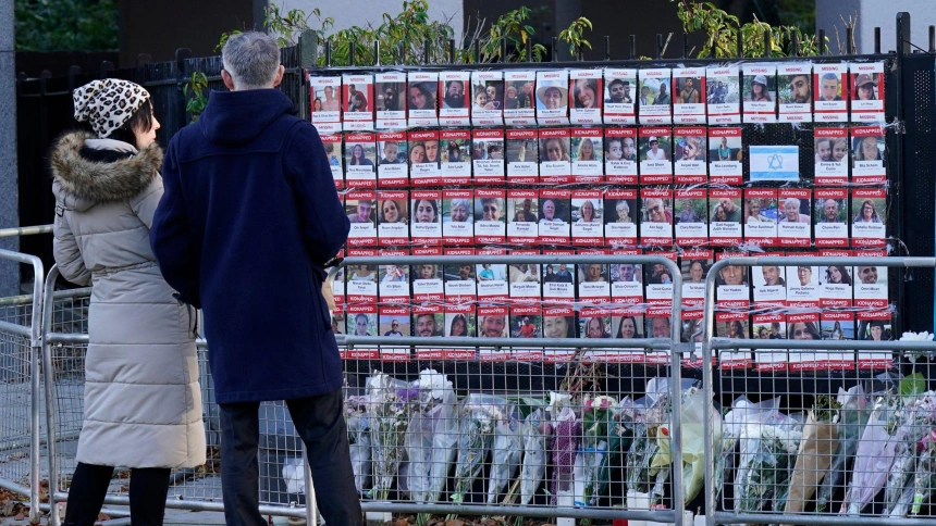 Dos ciudadanos ante la lista de los rehenes secuestrados por Hamás
