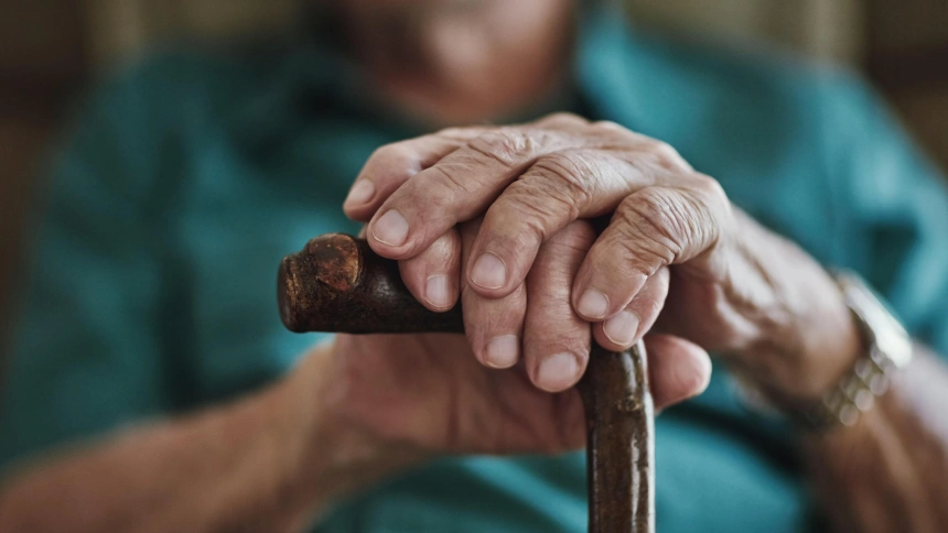 Hombre mayor reposando sus manos sobre un bastón