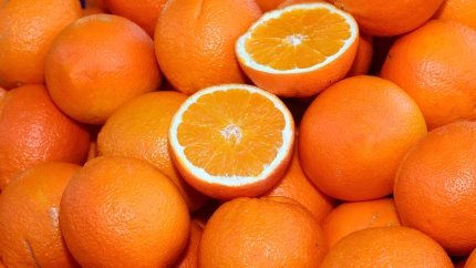 Fondo de muchas naranjas maduras y algunas cortadas por la mitad para la venta en la frutería