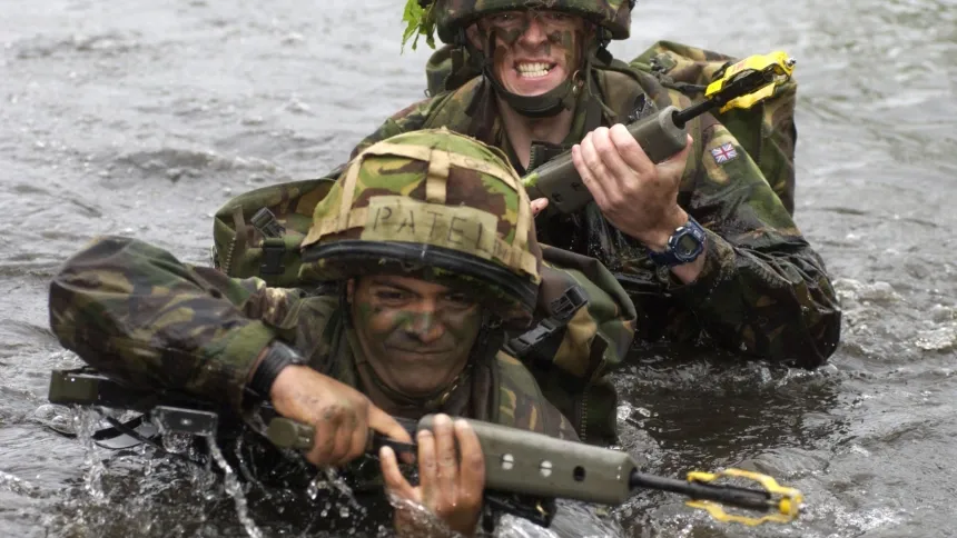 Militares cruzando el agua con armas entre las manos