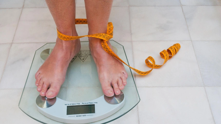 CNE3JY Mature woman weighing herself.