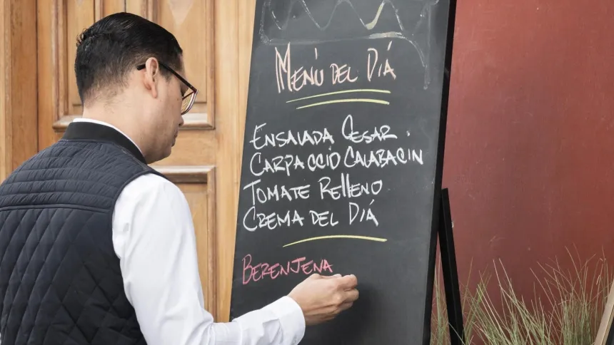 Un camarero apunta el menú del día de un restaurante en una pizarra