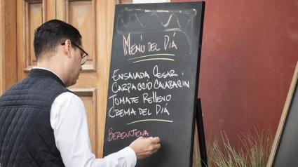 Un camarero apunta el menú del día de un restaurante en una pizarra