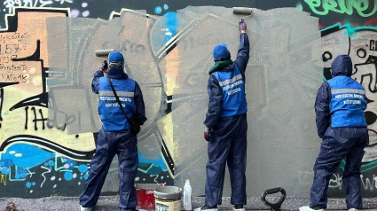 Jóvenes cubriendo una pared de grafitis para evitar sus multas