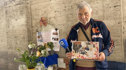 Paolo, sostieniendo su foto con el Papa Francisco frente al altar que hizo al Papa Francisco