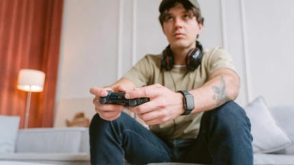 Joven jugando a videojuegos en el sofá de su casa