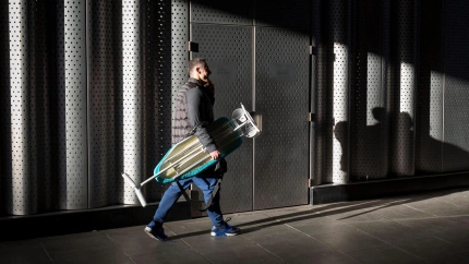 Un hombre carga con una tabla de planchar por la calle