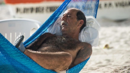 Un hombre dormido sobre una hamaca de la playa