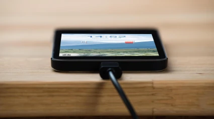 Un smartphone sin batería conectado a un cargador sobre una mesa de madera