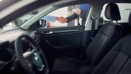 Apretón de manos para acordar la compra de un vehículo visto a través de la ventanilla del coche