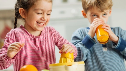 Niños haciendo y bebiendo zumo de naranja valenciana