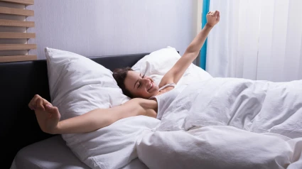 Una mujer se estira en la cama al despertarse