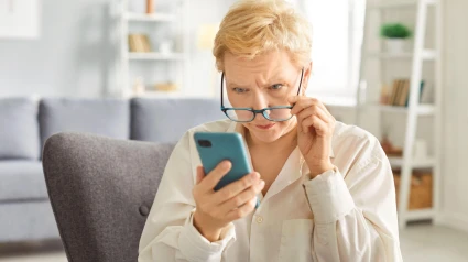 Una mujer mayor mira sospechosamente su teléfono móvil