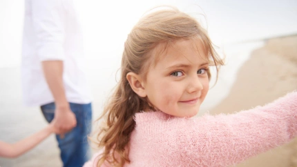 Una niña paseando por la playa con sus padres