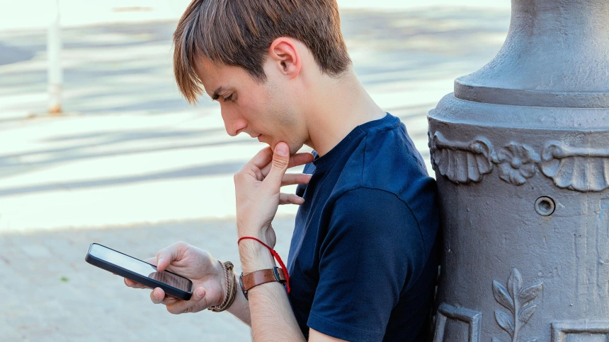 Un chico usando su teléfono móvil pensativo