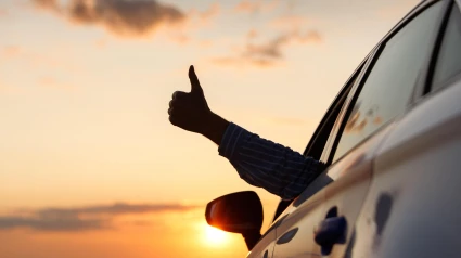 Un hombre sacando el pulgar por la ventanilla delantera de su coche