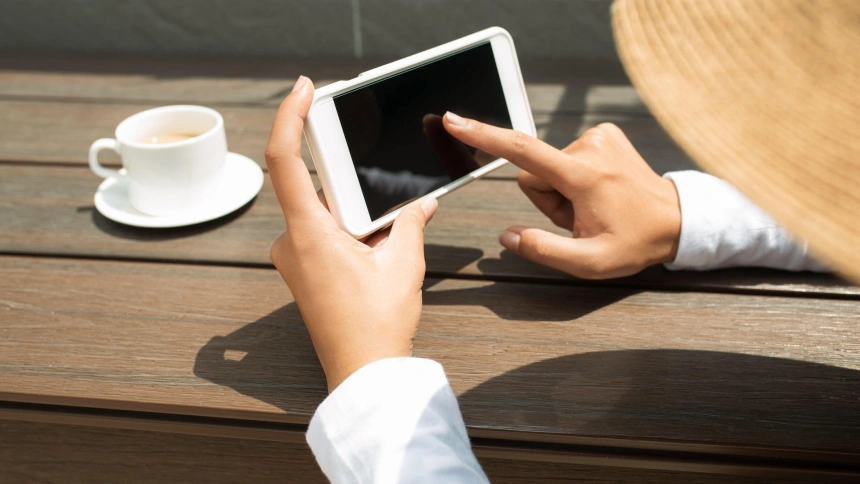 Una mujer sujetando su teléfono móvil al sol