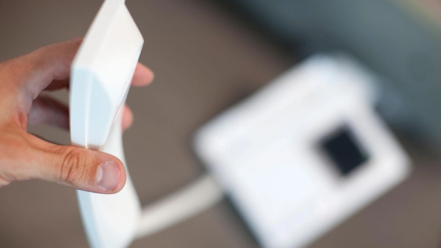 Una mano sostiene un teléfono fijo