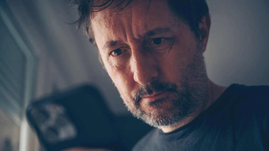 Un hombre mira su móvil sorprendido