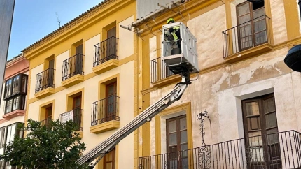 Operarios del Ayuntamiento revisan con una grúa la fachada de un edificio histórico en la plaza de España