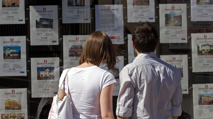 Una pareja mirando carteles de venta de pisos en una inmobiliaria