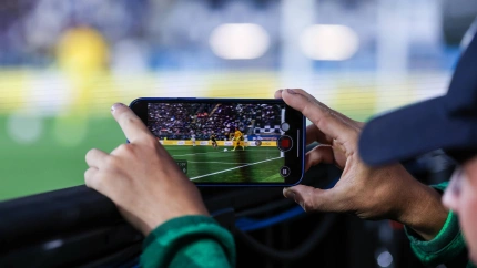 Un hombre graba un vídeo de un partido de fútbol con su teléfono móvil.