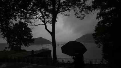 Un hombre se protege con el paraguas de una fuerte tormenta en el paseo de la Concha de San Sebastián