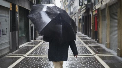 Una persona camina protegiéndose con un paraguas por la lluvia por el casco viejo de Pamplona