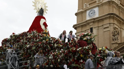 Varias personas colocan las flores a los pies de la Virgen del Pilar