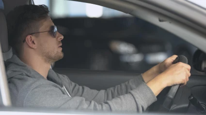 Conductor masculino que lleva gafas de sol polarizadas para proteger los ojos y conducir de forma segura