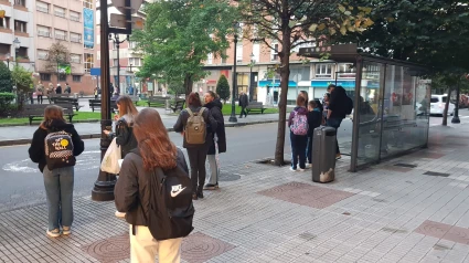 Usuarios del bus urbano esperando en una parada de EMTUSA, en Gijón