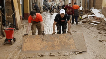 Vecinos de Paiporta limpian el lodo de una calle afectada,