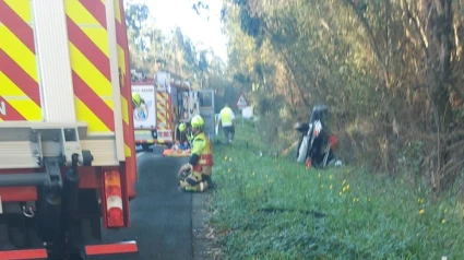 Intervención de los bomberos de Narón con el coche al fondo volcado