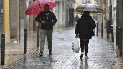 Unos viandantes se protegen de la lluvia con paraguas en Vinaroz, provincia de Castellón