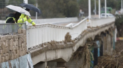 Dos técnicos evalúan bajo la lluvia el estado del puente de la localidad valenciana de Riba-roja