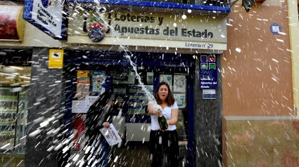 Una mujer salpica vino durante las celebraciones. Celebraciones de la lotería de Navidad 2018 de un cuarto premio del sorteo, Se ha vendido el número de Lotería 67774 en la Administración número 29 del Barrio de Santa Eulalia Dotado con 200.000 euros en cada serie