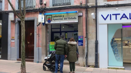 Una pareja frente a un establecimiento de Loterías y Apuestas del Estado durante los últimos preparativos de la Lotería de Navidad, el 21 de diciembre de 2023, en Oviedo, España