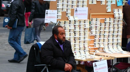 Un hombre se sienta junto a su puesto de venta de billetes de la Lotería de Navidad en la Plaza Puerta del Sol, en el centro de Madrid