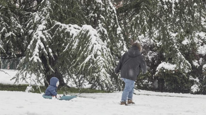 Foto de archivo de una mujer y un niño jugando con la nieve