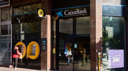 Muestra la fachada moderna de una sucursal de Caixa Bank, con elegantes líneas arquitectónicas y una marca destacada.